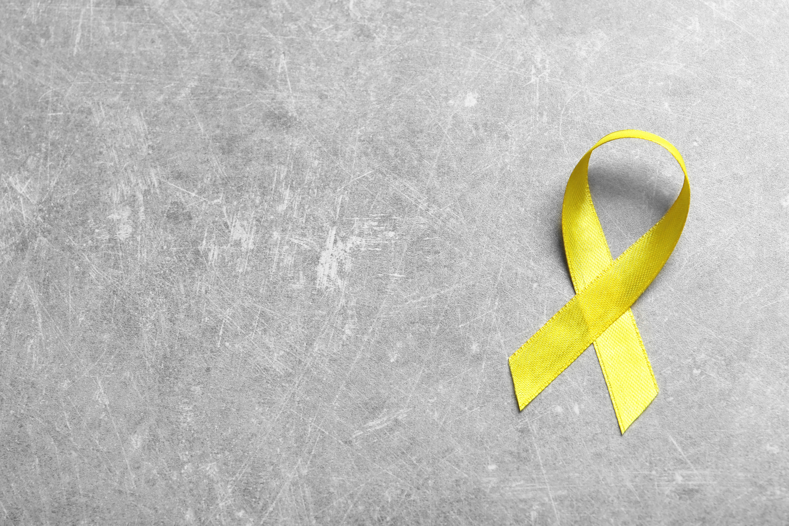 Yellow Ribbon on Grey Background, Top View. Cancer Awareness